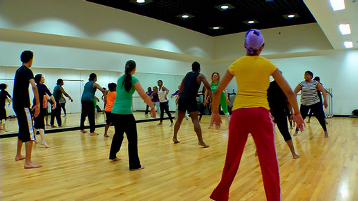 Group of dancers stepping side to side with arms pushing forward