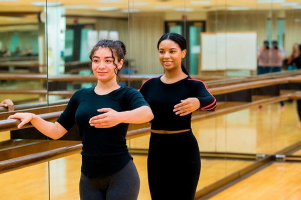 2 dancers standing at the ballet barre